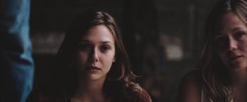 Movie still from “Martha Marcy May Marlene” (2011), directed by Sean Durkin – A woman with long brown hair is looking at the camera; Close Up shot, Low angle