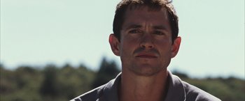 Movie still from “Martha Marcy May Marlene” (2011), directed by Sean Durkin – A person wearing a gray shirt; Close Up shot, Low angle