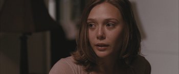 Movie still from “Martha Marcy May Marlene” (2011), directed by Sean Durkin – A person sitting down with her eyes wide open; Close Up shot, Over the shoulder angle