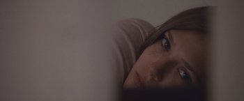 Movie still from “Martha Marcy May Marlene” (2011), directed by Sean Durkin – A young woman is laying on the bed looking at the camera; Close Up shot, High angle