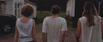 Movie still from “Martha Marcy May Marlene” (2011), directed by Sean Durkin – Two people standing in a dirt field near a building; Medium shot, Over the shoulder angle