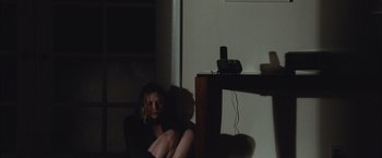 Movie still from “Martha Marcy May Marlene” (2011), directed by Sean Durkin – A woman sitting on a chair in a dark room; Medium shot, High angle