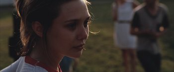 Movie still from “Martha Marcy May Marlene” (2011), directed by Sean Durkin – A woman's face in a grassy area; Close Up shot, Over the shoulder angle