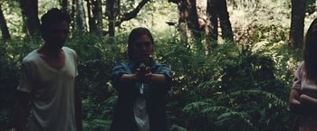 Movie still from “Martha Marcy May Marlene” (2011), directed by Sean Durkin – A woman is holding a gun in the woods; Medium shot, Over the shoulder angle