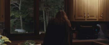 Movie still from “Martha Marcy May Marlene” (2011), directed by Sean Durkin – A woman standing in front of a window at night; Medium shot, Over the shoulder angle