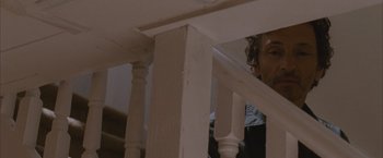 Movie still from “Martha Marcy May Marlene” (2011), directed by Sean Durkin – A man standing on top of a wooden railing next to stairs; Close Up shot, Low angle