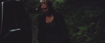Movie still from “Martha Marcy May Marlene” (2011), directed by Sean Durkin – A woman walking in the woods wearing a black jacket; Medium shot, Low angle