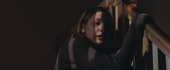 Movie still from “Martha Marcy May Marlene” (2011), directed by Sean Durkin – A woman in a sweater looking out of a window; Close Up shot, Low angle