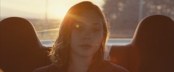A young woman is sitting in the back of a car