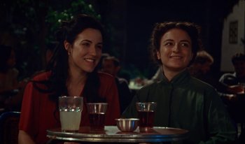 Movie still from “Martin Eden” (2019), directed by Pietro Marcello – Two women are sitting at a table with drinks; Medium shot, High angle