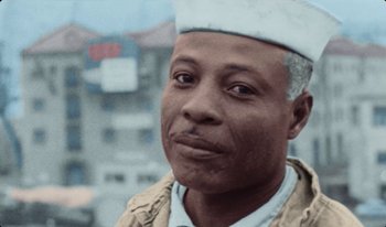 Movie still from “Martin Eden” (2019), directed by Pietro Marcello – An older man wearing a white hat looking at the camera; Close Up shot, High angle