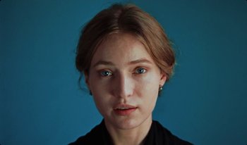 Movie still from “Martin Eden” (2019), directed by Pietro Marcello – A young woman with blue eyes is posing for a picture; Close Up shot, Overhead angle