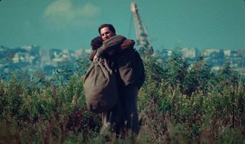 Movie still from “Martin Eden” (2019), directed by Pietro Marcello – A man and woman hugging in a field; Wide shot, High angle