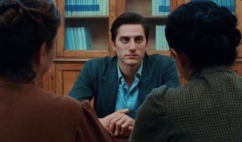 Movie still from “Martin Eden” (2019), directed by Pietro Marcello – A man sitting in front of two other people; Close Up shot, Over the shoulder angle