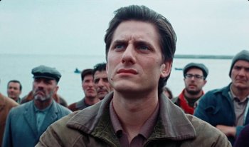 Movie still from “Martin Eden” (2019), directed by Pietro Marcello – A man standing in front of a group of people; Close Up shot, Low angle