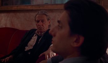Movie still from “Martin Eden” (2019), directed by Pietro Marcello – A man and a man in a suit sitting on a red couch; Close Up shot, Over the shoulder angle