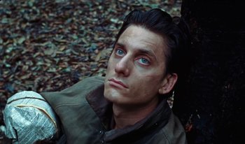 Movie still from “Martin Eden” (2019), directed by Pietro Marcello – A person sitting on a tree trunk; Close Up shot, High angle