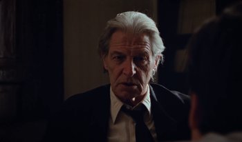 Movie still from “Martin Eden” (2019), directed by Pietro Marcello – An older man in a black suit and white shirt; Close Up shot, Over the shoulder angle
