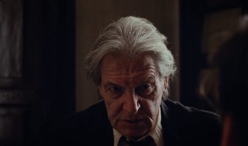 Movie still from “Martin Eden” (2019), directed by Pietro Marcello – An older man with a white beard looking at the camera; Close Up shot, Low angle