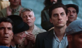 Movie still from “Martin Eden” (2019), directed by Pietro Marcello – A man in a suit looking up at the sky; Close Up shot, Low angle