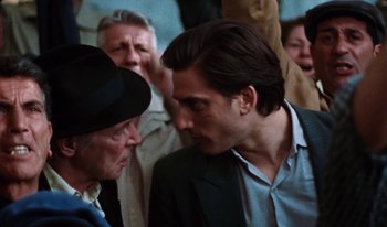 Movie still from “Martin Eden” (2019), directed by Pietro Marcello – A man in a suit and a man in a blue hat; Close Up shot, Over the shoulder angle