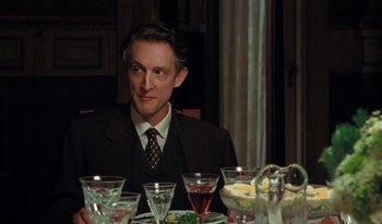 Movie still from “Martin Eden” (2019), directed by Pietro Marcello – A man sitting at a dinner table in front of a plate of food; Medium shot, Over the shoulder angle