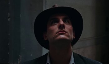 Movie still from “Martin Eden” (2019), directed by Pietro Marcello – A person wearing a suit and a hat; Close Up shot, Low angle