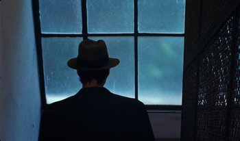 Movie still from “Martin Eden” (2019), directed by Pietro Marcello – A man wearing a hat looking out of a window; Close Up shot, Over the shoulder angle