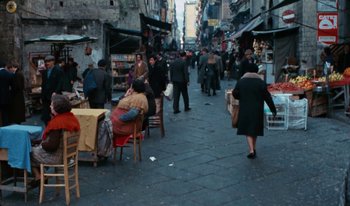 Movie still from “Martin Eden” (2019), directed by Pietro Marcello – A group of people walking down a street; Wide shot, High angle