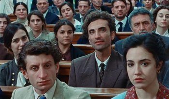 Movie still from “Martin Eden” (2019), directed by Pietro Marcello – A group of people sitting in a room; Close Up shot, High angle