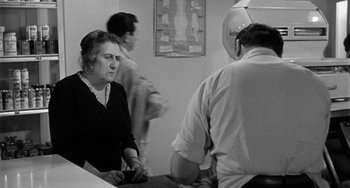 Movie still from “Marty” (1955), directed by Delbert Mann – An older woman sitting at a table in front of two other people; Medium shot, Over the shoulder angle