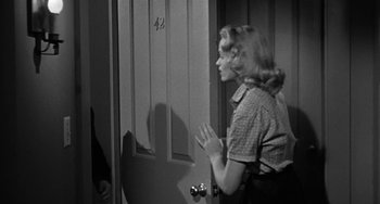 Movie still from “Marty” (1955), directed by Delbert Mann – A black and white photo of a woman standing in front of a door; Medium shot, Over the shoulder angle