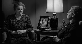 Movie still from “Marty” (1955), directed by Delbert Mann – Two people sitting at a table with a lamp and a picture; Medium shot, Over the shoulder angle