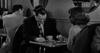 Movie still from “Marty” (1955), directed by Delbert Mann – A man sitting at a table with a cup of coffee; Medium shot, Over the shoulder angle