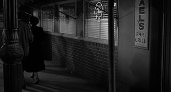 Movie still from “Marty” (1955), directed by Delbert Mann – A black and white photo of a person standing in front of a building; Wide shot, Over the shoulder angle