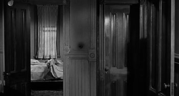 Movie still from “Marty” (1955), directed by Delbert Mann – A black and white photo of a room with a bed in the background; Medium shot, High angle