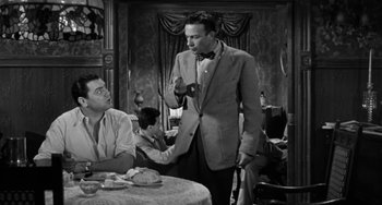 Movie still from “Marty” (1955), directed by Delbert Mann – A man in a suit and bow tie standing at a table; Medium shot, Over the shoulder angle