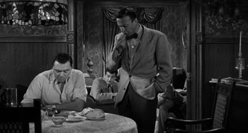 Movie still from “Marty” (1955), directed by Delbert Mann – An old photo of a man standing at a dinner table; Medium shot, High angle