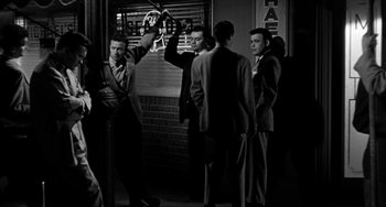 Movie still from “Marty” (1955), directed by Delbert Mann – A black and white photo of a group of men standing around; Wide shot, Over the shoulder angle