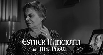 Movie still from “Marty” (1955), directed by Delbert Mann – An older woman putting on a pair of earrings in front of a mirror; Medium shot, Low angle