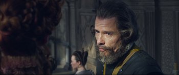 Movie still from “Mary Queen of Scots” (2018), directed by Josie Rourke – A man with long hair and a goatee stares into the distance; Close Up shot, Over the shoulder angle