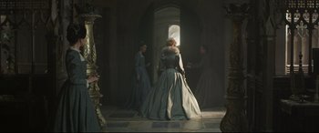 Movie still from “Mary Queen of Scots” (2018), directed by Josie Rourke – A woman in a long dress standing next to a door; Wide shot, Over the shoulder angle