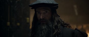 Movie still from “Mary Queen of Scots” (2018), directed by Josie Rourke – A man with long hair and a beard wearing a hat; Close Up shot, Over the shoulder angle