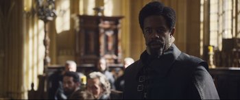 Movie still from “Mary Queen of Scots” (2018), directed by Josie Rourke – A man with a beard standing in front of a group of people; Close Up shot, Over the shoulder angle