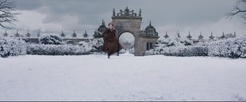 Movie still from “Mary Queen of Scots” (2018), directed by Josie Rourke – A woman in a brown dress jumping in the air in front of an archway in the snow; Extreme Wide shot, High angle