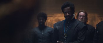 Movie still from “Mary Queen of Scots” (2018), directed by Josie Rourke – A man in a black suit standing next to another man in a black suit; Medium shot, Over the shoulder angle