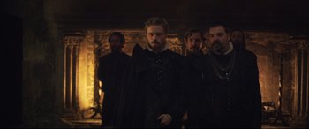 Movie still from “Mary Queen of Scots” (2018), directed by Josie Rourke – A group of men standing next to each other in front of a fireplace; Medium shot, Over the shoulder angle