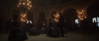 Movie still from “Mary Queen of Scots” (2018), directed by Josie Rourke – A group of people sitting in a room with chandeliers in the background; Wide shot, High angle