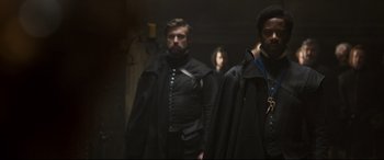 Movie still from “Mary Queen of Scots” (2018), directed by Josie Rourke – A group of men in black suits and black coats; Medium shot, Over the shoulder angle