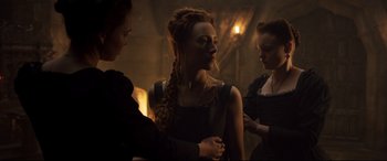 Movie still from “Mary Queen of Scots” (2018), directed by Josie Rourke – A woman with long red hair is standing next to two other women; Medium shot, Over the shoulder angle